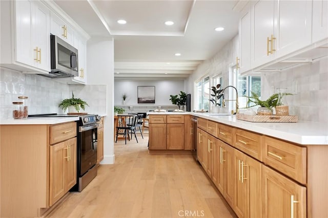 kitchen featuring light hardwood / wood-style floors, kitchen peninsula, stainless steel appliances, white cabinets, and sink