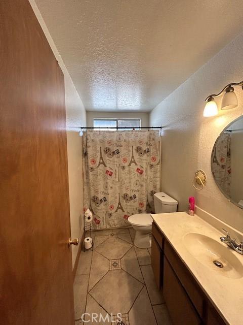 bathroom with curtained shower, a textured ceiling, tile patterned floors, vanity, and toilet