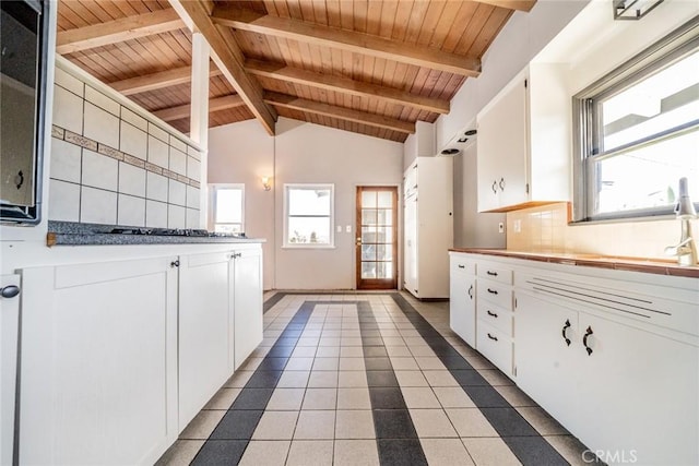 kitchen featuring tile patterned floors, sink, beamed ceiling, white cabinetry, and wood ceiling