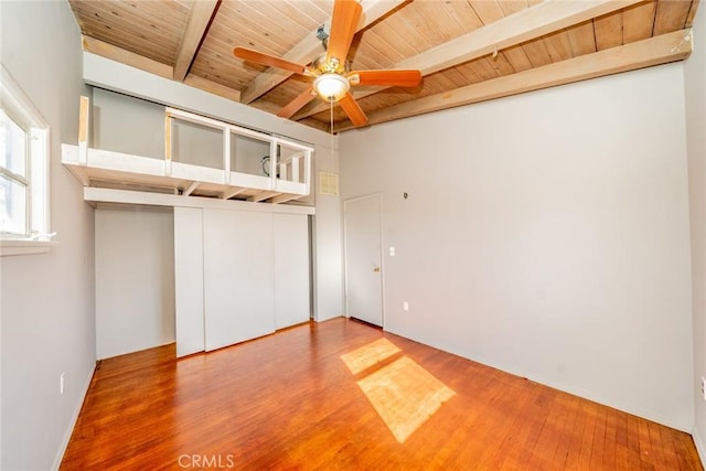 unfurnished bedroom featuring hardwood / wood-style flooring, ceiling fan, wooden ceiling, a closet, and beamed ceiling