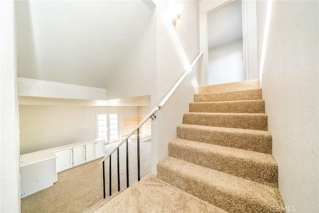 stairway with vaulted ceiling and carpet