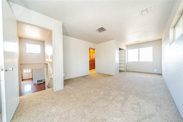 empty room with plenty of natural light and carpet flooring