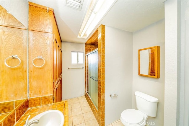 bathroom featuring an enclosed shower, tile patterned flooring, and toilet