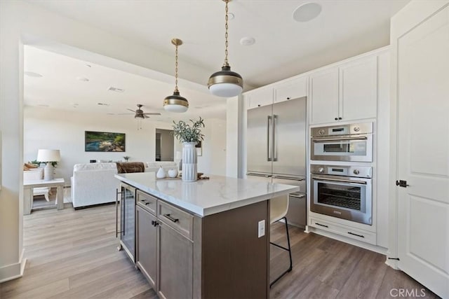 kitchen with stainless steel appliances, a kitchen breakfast bar, wine cooler, white cabinets, and a center island