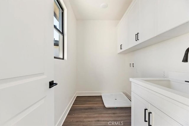 clothes washing area featuring dark hardwood / wood-style flooring, sink, hookup for a washing machine, and cabinets