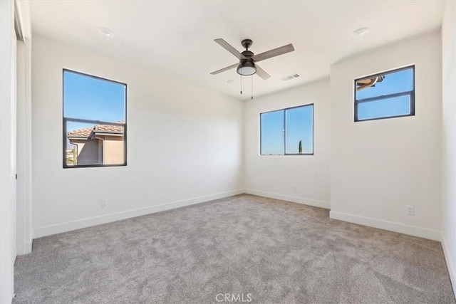 empty room with ceiling fan and light carpet