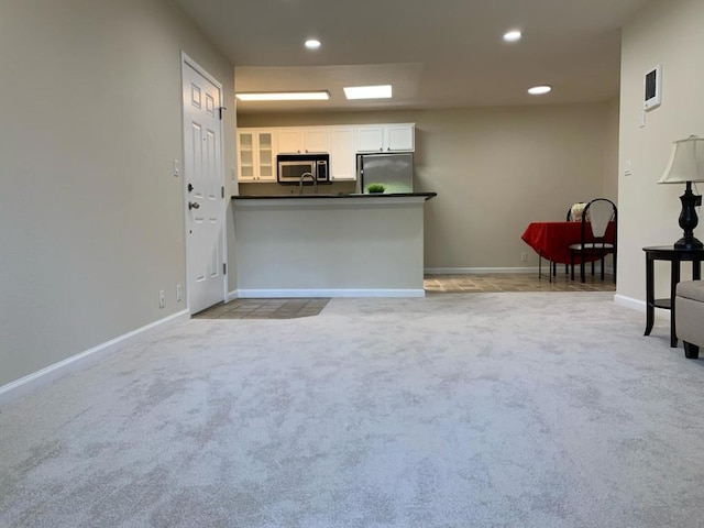 kitchen featuring light colored carpet, white cabinetry, stainless steel appliances, and kitchen peninsula