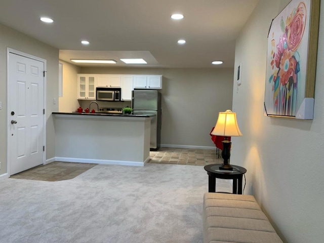 kitchen featuring light colored carpet, kitchen peninsula, appliances with stainless steel finishes, and white cabinetry