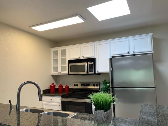 kitchen featuring sink, white cabinetry, stainless steel appliances, and dark stone counters