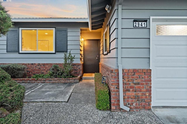 exterior entry at dusk featuring a garage