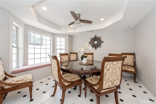 dining area featuring ceiling fan and a raised ceiling