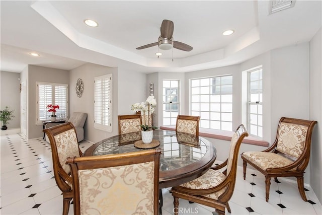 dining area featuring ceiling fan and a tray ceiling