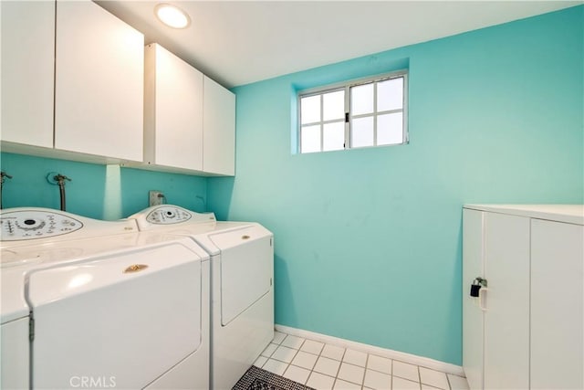 clothes washing area with washer and clothes dryer, light tile patterned floors, and cabinets