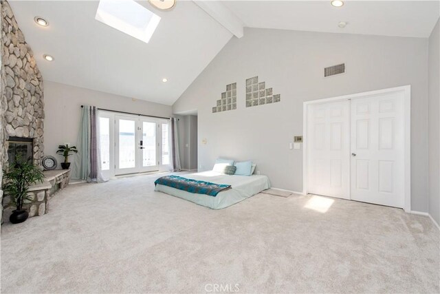 carpeted bedroom featuring high vaulted ceiling, a skylight, a fireplace, and beamed ceiling