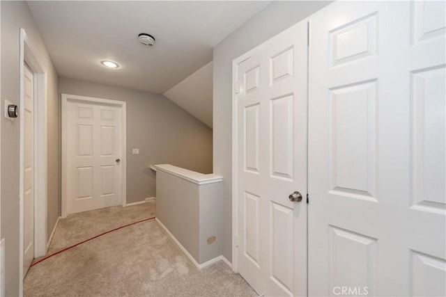 hall featuring lofted ceiling and light colored carpet