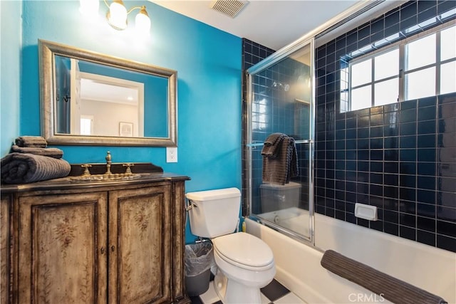 full bathroom featuring toilet, bath / shower combo with glass door, and vanity