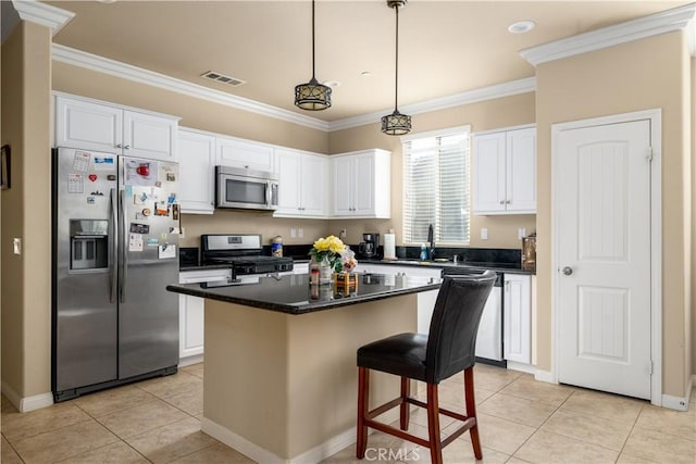 kitchen featuring white cabinets, appliances with stainless steel finishes, a center island, light tile patterned floors, and crown molding