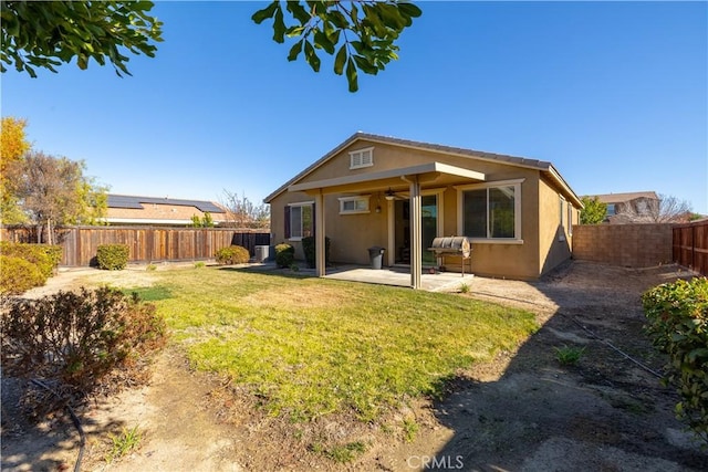 rear view of house with ceiling fan, a patio area, and a yard