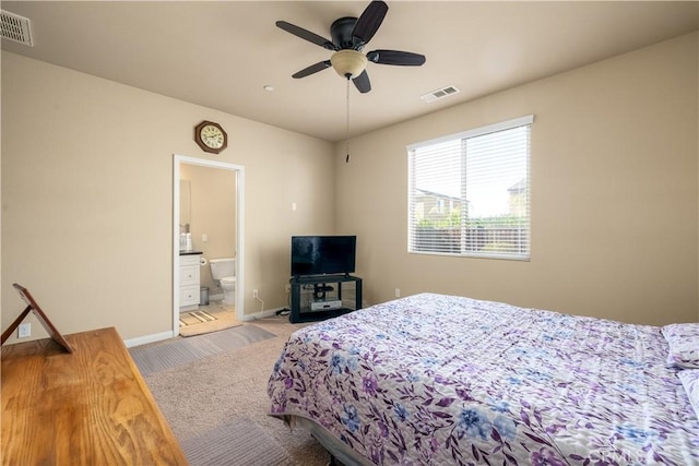 bedroom with ceiling fan, ensuite bathroom, and light carpet