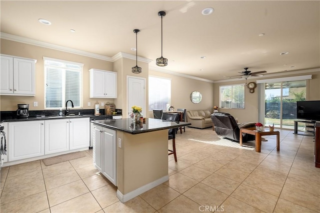 kitchen with light tile patterned flooring, ceiling fan, a kitchen island, and decorative light fixtures