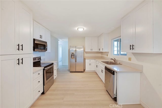 kitchen featuring white cabinets, sink, stainless steel appliances, and light hardwood / wood-style flooring