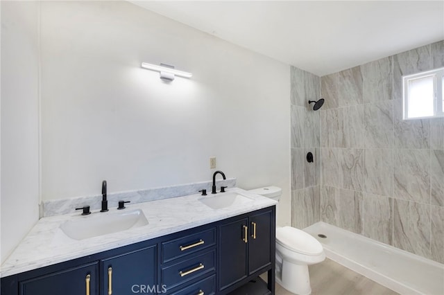 bathroom with toilet, tiled shower, hardwood / wood-style flooring, and vanity