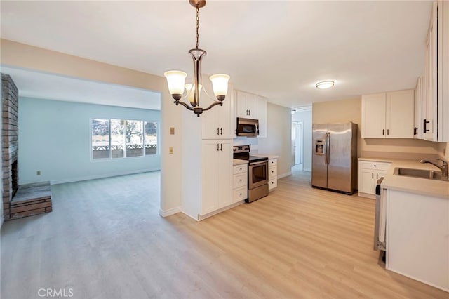 kitchen featuring pendant lighting, sink, white cabinetry, and stainless steel appliances