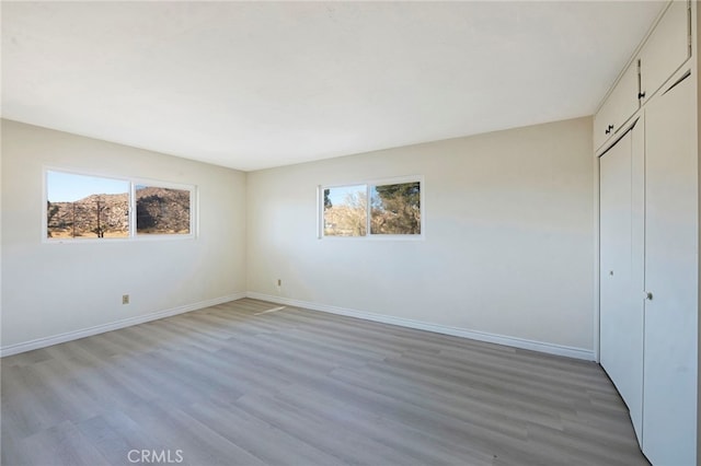 unfurnished bedroom with a closet, wood-type flooring, and multiple windows