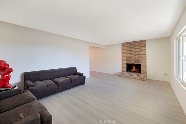 living room with a stone fireplace and light wood-type flooring