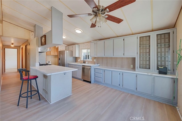 kitchen with ceiling fan, kitchen peninsula, white cabinetry, light wood-type flooring, and stainless steel appliances