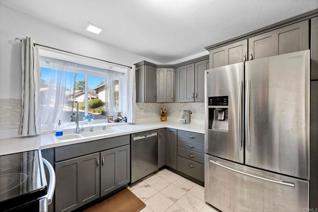 kitchen with sink, decorative backsplash, gray cabinets, and appliances with stainless steel finishes