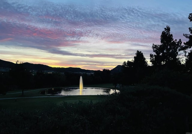 yard at dusk featuring a water and mountain view