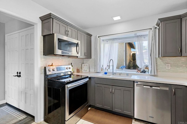 kitchen with stainless steel appliances, sink, tasteful backsplash, and gray cabinetry