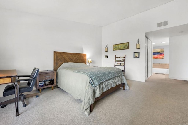 bedroom with ensuite bath and light carpet