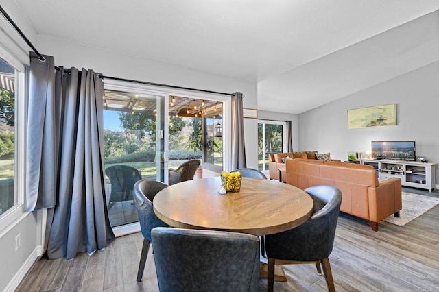 dining room with vaulted ceiling and wood-type flooring