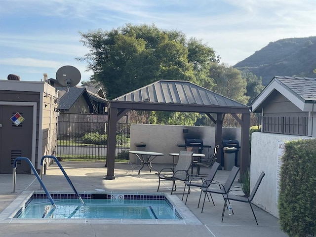 view of swimming pool with a gazebo, an in ground hot tub, a mountain view, and area for grilling