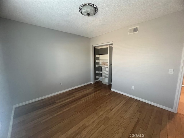 unfurnished bedroom featuring a closet, dark hardwood / wood-style flooring, and a textured ceiling