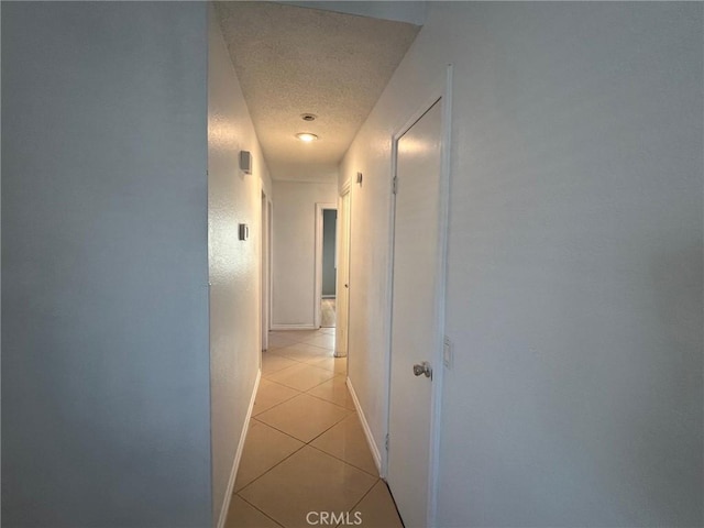 hallway with a textured ceiling and light tile patterned floors