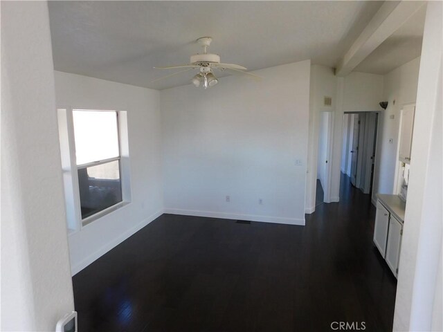 empty room with ceiling fan, dark wood-type flooring, and beamed ceiling