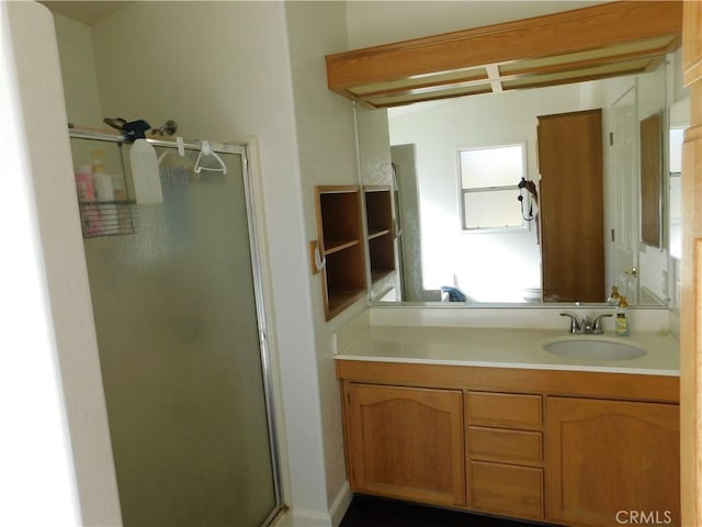 bathroom featuring a shower with shower door and vanity