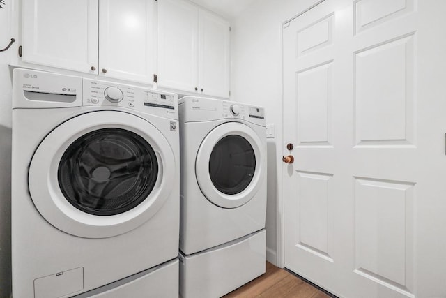 clothes washing area featuring washing machine and dryer, cabinets, and light hardwood / wood-style floors