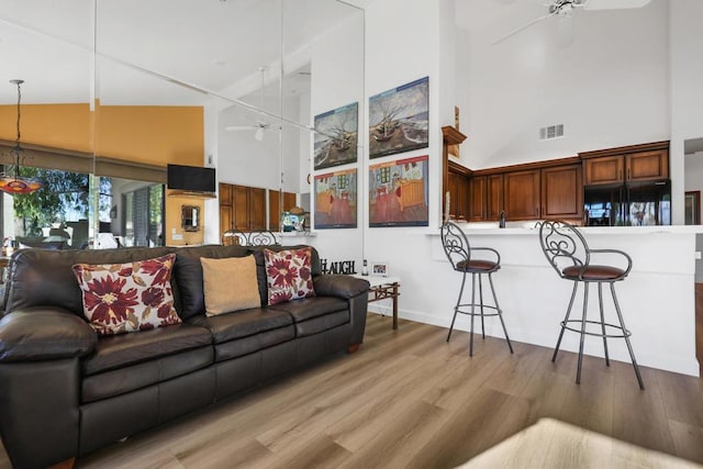 living room with high vaulted ceiling, ceiling fan, and light hardwood / wood-style flooring