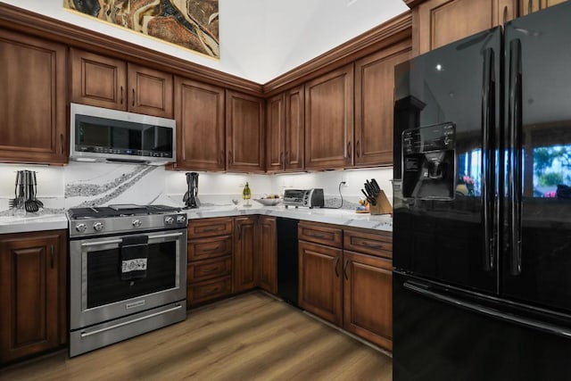 kitchen featuring appliances with stainless steel finishes, hardwood / wood-style flooring, and light stone counters