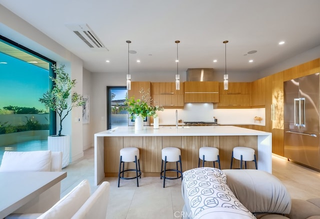 kitchen with pendant lighting, a kitchen bar, stainless steel built in refrigerator, and a spacious island