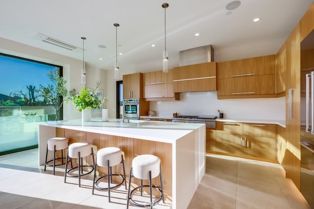 kitchen with decorative light fixtures, wall chimney range hood, a breakfast bar area, and light tile patterned flooring