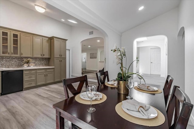 dining space with high vaulted ceiling and light hardwood / wood-style floors