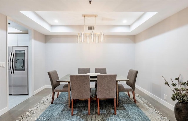 dining room with baseboards, visible vents, and a tray ceiling