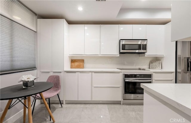 kitchen featuring recessed lighting, stainless steel appliances, white cabinetry, light countertops, and modern cabinets