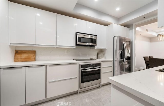 kitchen with stainless steel appliances, modern cabinets, white cabinetry, and decorative backsplash