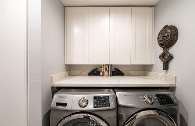 clothes washing area with cabinets and washer and clothes dryer